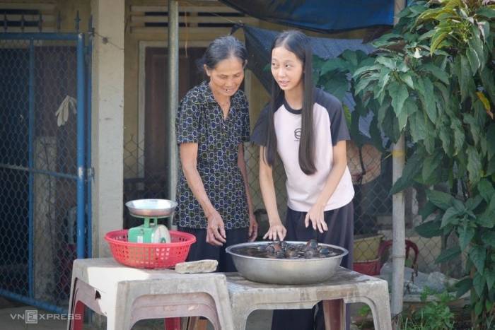 Thới Ngọc Trân Châu phụ bà ngoại bán ốc trước nhà. Ảnh: Phạm Linh