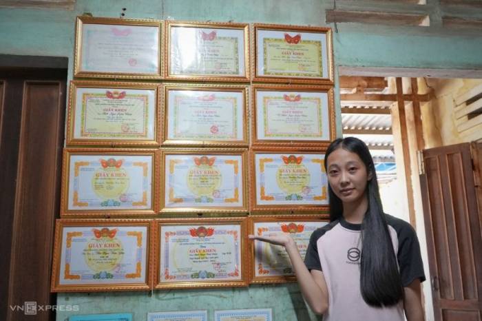 Châu bên bức tường treo giấy khen của cô ở nhà ông bà ngoại. Ảnh: Phạm Linh