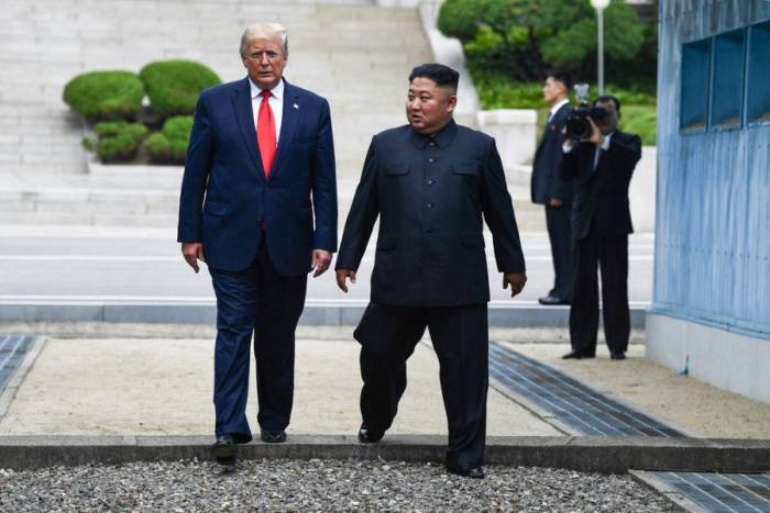 Tổng thống Mỹ Donald Trump (trái) và lãnh đạo Triều Tiên Kim Jong-un bước qua giới tuyến liên triều tại Bàn Môn Điếm ngày 30/6/2019. Ảnh: AFP