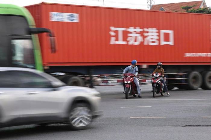 Hai xe máy dừng giữa nút giao trong khi xe container chạy qua. Ảnh: Phước Tuấn