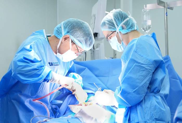 Phó giáo sư Vĩnh (bên trái) cùng êkíp phẫu thuật cắt u khí quản cho người bệnh. Ảnh: Bệnh viện Đa khoa Tâm Anh