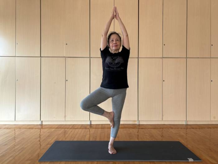 Người phụ nữ trung niên tư thế yoga cái cây giúp duy trì thăng bằng khi lớn tuổi. Ảnh: Quỳnh Dung