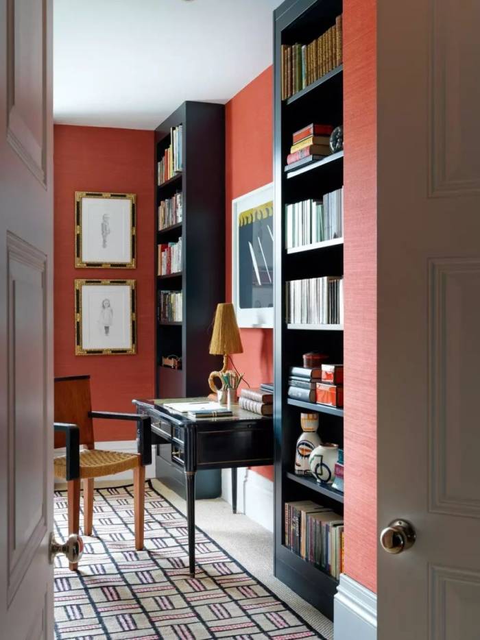 Góc bàn viết không bố trí màn hình, sử dụng bàn gỗ kiểu cổ điển, ghế đan, đèn bàn và hệ kệ sách âm tường. Tường màu đỏ đất, nội thất gỗ tối màu, tranh khung cổ và thảm họa tiết tạo sắc thái hoài cổ, phù hợp xu hướng đưa các hoạt động đọc, viết trở lại không gian sống, giảm phụ thuộc thiết bị số. Ảnh: Simon Brown