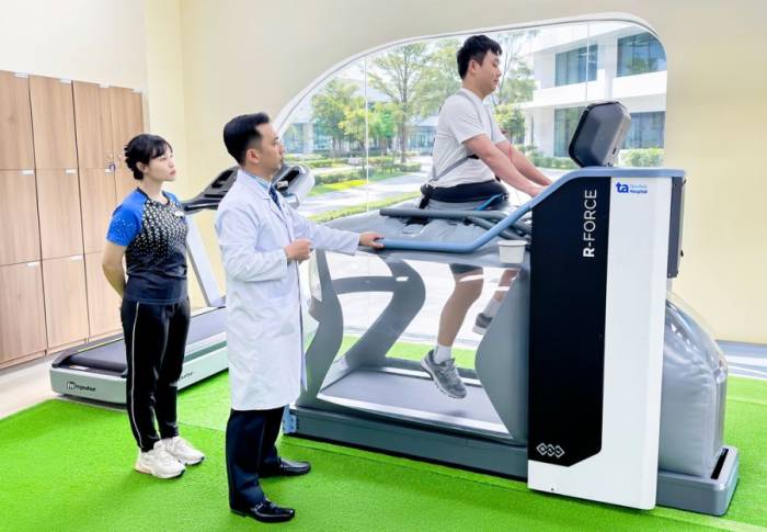 Bác sĩ Vũ đang hướng dẫn người bệnh tập phục hồi chức năng trên hệ thống máy R-Force không trọng lực hiện đại. Ảnh: Bệnh viện Đa khoa Tâm Anh