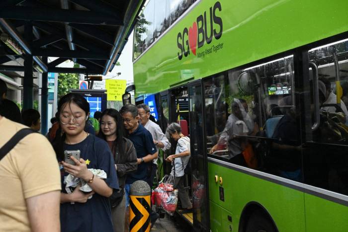 Hành khách xuống xe buýt tại Singapore ngày 21/9. Ảnh: AFP