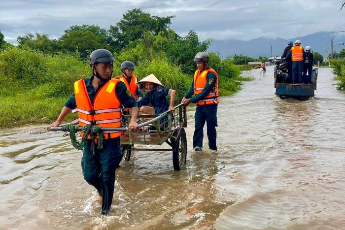 Lực lượng dân quân hỗ trợ người dân di chuyển qua khu vực ngập nước. Ảnh: Tư Huynh