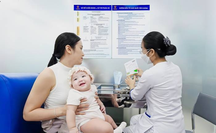 Chị Trần Thị Nga, phường Bình Đông, TPHCM đưa con gái 6 tháng tuổi đến VNVC Quận 8 tiêm vắc xin phòng tay chân miệng. Ảnh: Trung Thái
