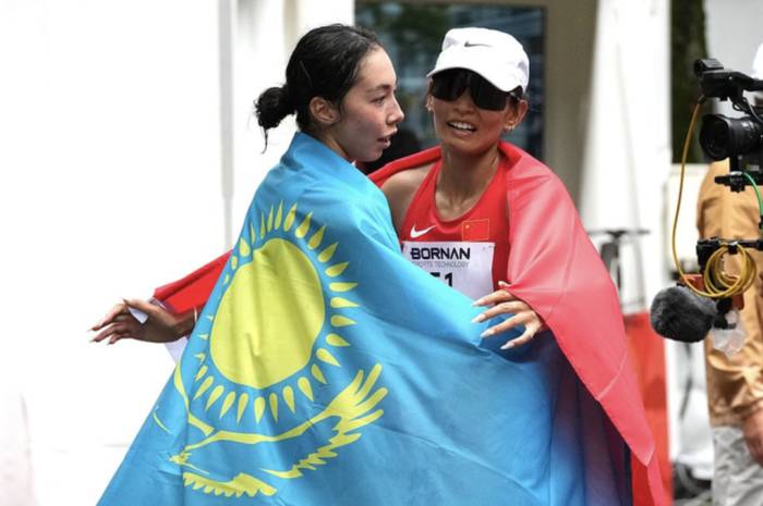 Yasmina Toxanbayeva (trái) và Dan Zengquzong ôm nhau ăn mừng sau chung kết marathon đi bộ nữ ASIAD 2026. Ảnh: Sina