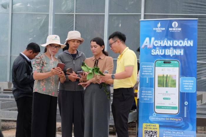 Bà con được hướng dẫn thực hành tính năng chẩn đoán sâu bệnh trên ứng dụng 2Nông tại vườn Robusta. Ảnh: Phân bón Cà Mau