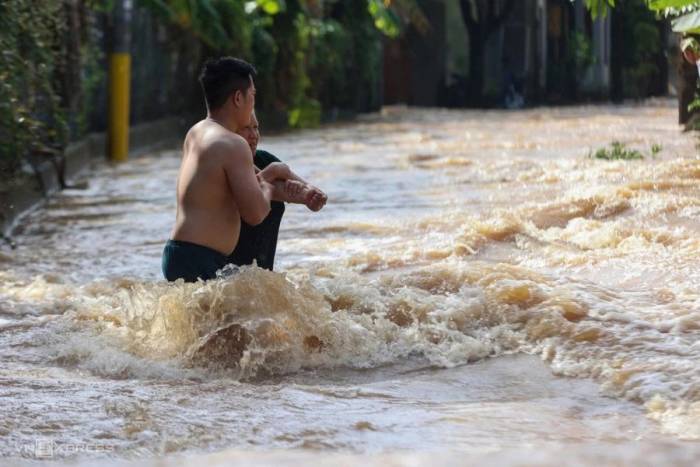 Người dân Phước Tân dìu nhau qua đoạn nước chảy siết ở khu dân cư. Ảnh: Phước Tuấn