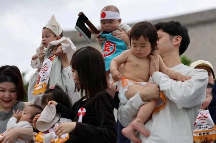 Các em bé cùng cha mẹ tham gia cuộc thi sumo tại chùa Sensoji ở Tokyo hôm 25/4. Ảnh: Reuters