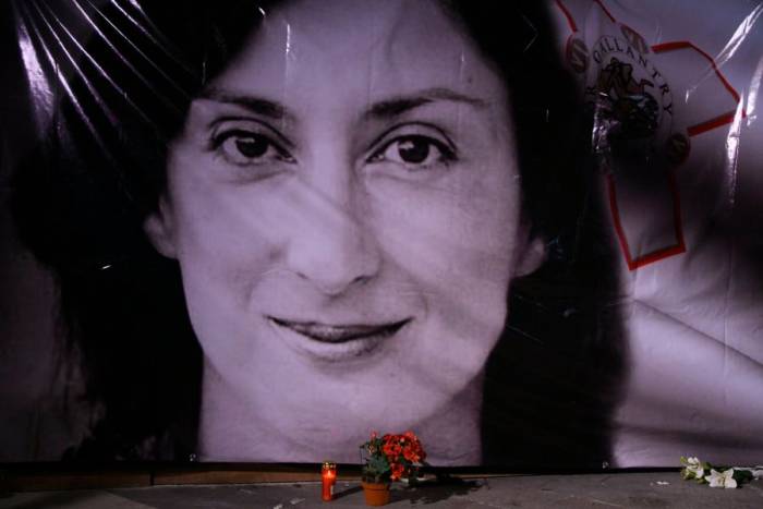 Hoa và nến được đặt trước bức chân dung của nữ nhà báo điều tra Daphne Caruana Galizia trong buổi tưởng niệm bên ngoài tòa án ở Valletta, Malta hồi năm 2018. Ảnh: AP