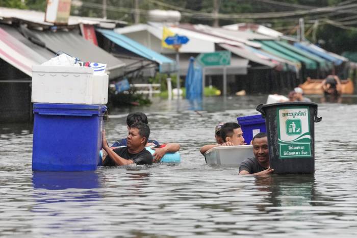 Người dân di chuyển qua vùng nước ngập sâu ở Bangkok, Thái Lan ngày 27/9. Ảnh: AP
