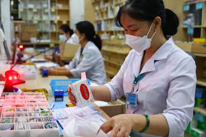 Nhân viên y tế tại nhà thuốc phát thuốc cho bệnh nhân. Ảnh: Như Quỳnh