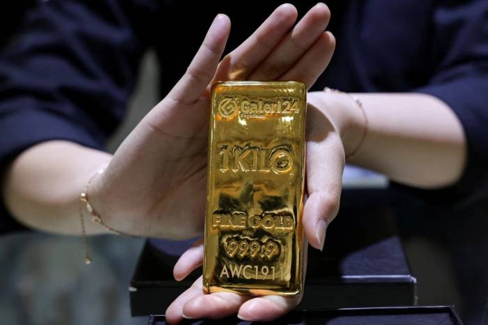 Một nhân viên đang giới thiệu thỏi vàng nặng 1kg tại cửa hàng trang sức ở Jakarta, Indonesia. Ảnh: Reuters