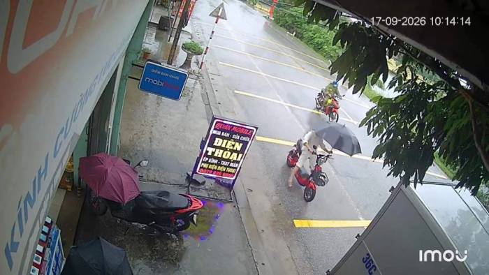 Bé gái cầm ô khi đi xe đạp điện, tông xe tải đang đỗ