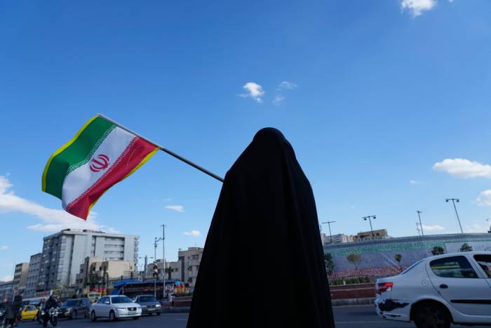 Người phụ nữ cầm cờ Iran trên đường phố ở Tehran hôm 30/3. Ảnh: AP