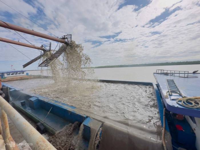 Cát biển sau khi khai thác được rửa mặn, bơm qua sà lan tại sông Hậu. Ảnh: An Bình