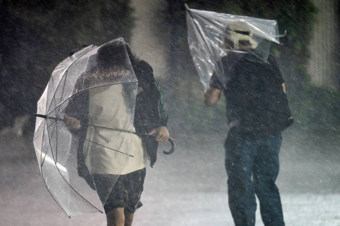 Mưa và gió lớn làm ô của người đi đường biến dạng tại Chiba ngày 21/9. Ảnh: AFP