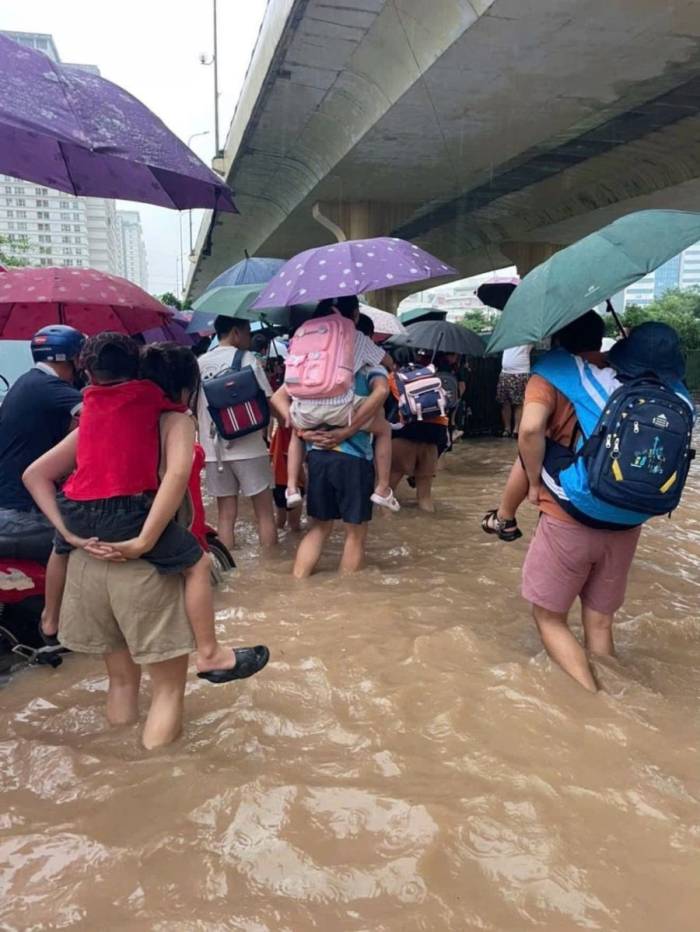 Cư dân chung cư Xuân Mai Complex lội nước cõng con đi học. Ảnh trong nhóm cư dân