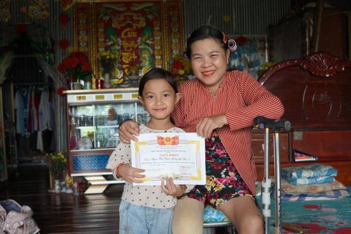 Thiên Hồng bên mẹ và giấy khen năm học trước. Ảnh: Ngọc Hân