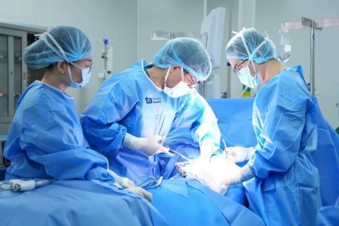 Phó giáo sư Vĩnh (giữa) cùng êkíp phẫu thuật cho người bệnh. Ảnh: Bệnh viện cung cấp