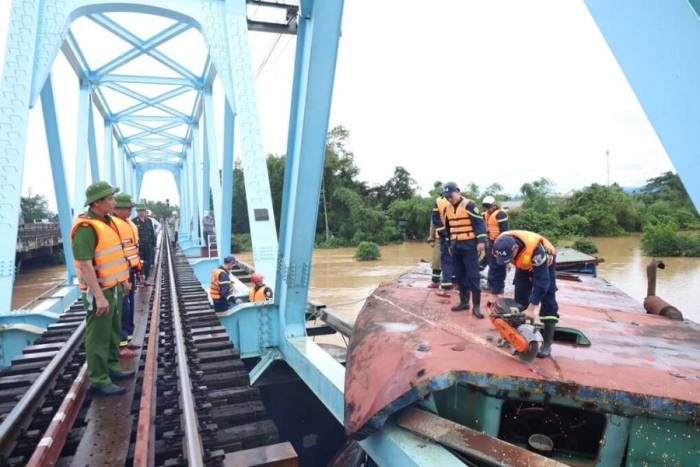 Cảnh sát chữa cháy cắt nóc cabin sà lan mắc kẹt vào cầu đường sắt Mỹ Chánh. Ảnh: Khôi Trần