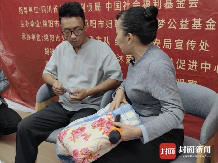 Bà Liu Huaqing trao cho con tấm chăn tự may cùng những bức ảnh chụp anh từ lúc 100 ngày tuổi, tại buổi đoàn tụ tại Công an thành phố Mianyang (Tứ Xuyên) ngày 15/9. Ảnh: CBGC