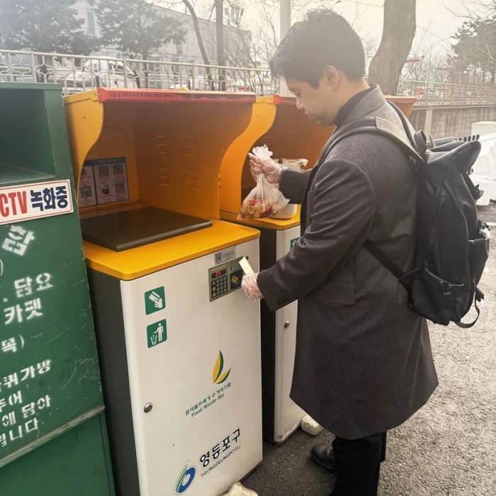 Seunghwan Hong quẹt thẻ để vứt rác vào hệ thống thu gom rác hữu cơ dưới tòa chung cư ở Seoul. Ảnh: BBC