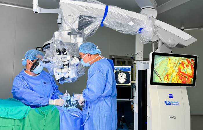 Các bác sĩ đang loại bỏ u não ác tính dưới hỗ trợ của công nghệ phát sáng huỳnh quang fluorescein trên kính vi phẫu AI Zeiss Kinevo 900. Ảnh: Bệnh viện Tâm Anh