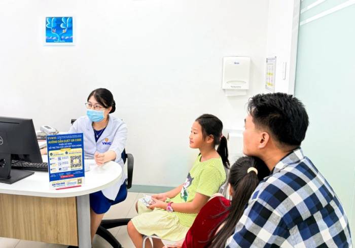Một gia đình đưa hai con đến rà soát lịch sử tiêm chủng và được tư vấn các mũi cần bổ sung trước năm học mới. Ảnh: Minh Trung