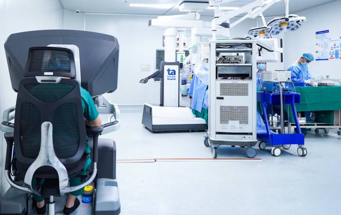 Bác sĩ Liên (ngồi) điều khiển robot Da Vinci Xi phẫu thuật khối u tuyến thượng thận cho anh Hoàng. Ảnh: Bệnh viện Đa khoa Tâm Anh