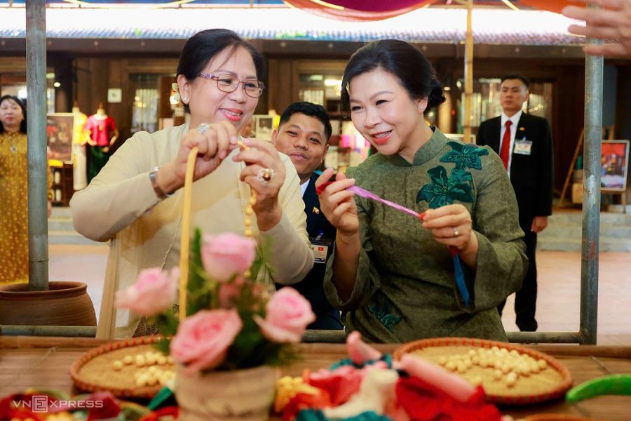 Hai phu nhân trải nghiệm xâu vòng lụa. Ảnh: Giang Huy