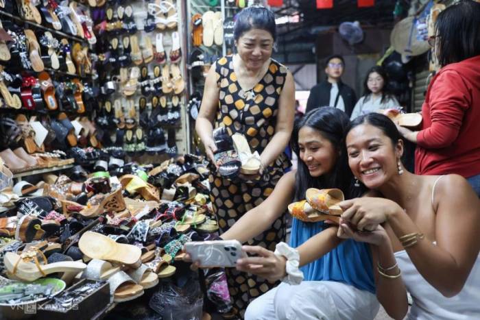 Khách nước ngoài rủ nhau đến chợ Tân Định đóng guốc mộc dịp hè. Ảnh: Quỳnh Trần