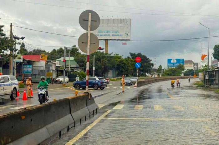 CSGT Công an tỉnh Lâm Đồng túc trực hướng dẫn xe cộ lưu thông qua đoạn quốc lộ 1A bị ngập. Ảnh: Tư Huynh