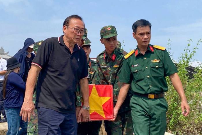 Ông Võ Đình Thế (bên trái), cùng đại diện Bộ Chỉ huy quân sự TP Đà Nẵng di chuyển các hài cốt vừa cất bốc tại khu mộ tập thể ở xã Thu Bồn về xã Hiệp Đức chuẩn bị cho Lễ truy điệu. Ảnh: NVCC