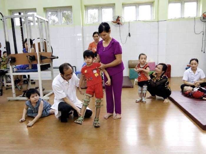 Bác sĩ Lê Thành Đô kiểm tra chân cho một bệnh nhi ở Ba Vì, Hà Nội, thử đứng bằng nẹp năm 2018. Ảnh: Nhân vật cung cấp