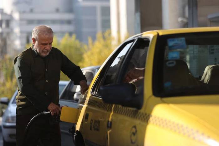 Một người đàn ông đang đổ xăng tại Tehran tháng 12/2025. Ảnh: Reuters