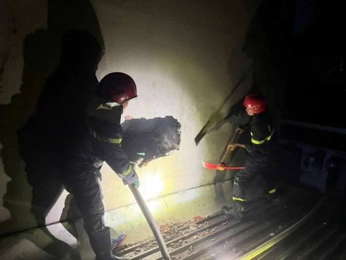 Lính cứu hỏa đục tường để thoát khói, xịt nước khống chế đám cháy từ tầng ba. Ảnh: Lam Anh