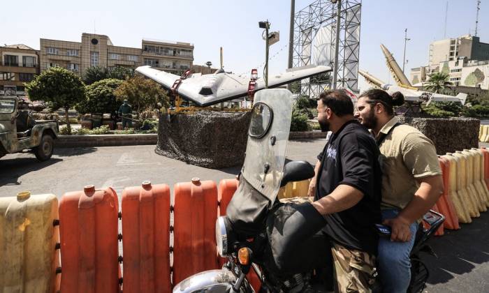 Hai người đàn ông Iran đi xe máy ngang qua các máy bay không người lái quân sự được trưng bày tại quảng trường Baharestan ở Tehran hôm 28/9. Ảnh: AFP
