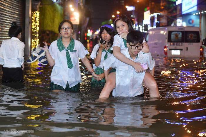 Nhóm học sinh THPT Thăng Long tan học đúng lúc đường ngập sâu. Ảnh: Thanh Tùng