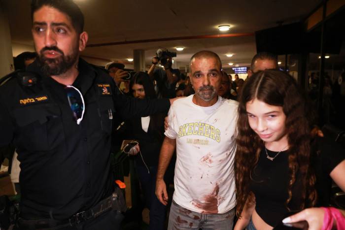 Yaniv Hayoun, hành khách người Israel đã tham gia khống chế cơ phó chuyến bay Flydubai, mặc chiếc áo phông trắng dính máu, được chào đón khi tới cổng sân bay Ben Gurion gần Tel Avi, Israel, ngày 30/9. Ảnh: AP
