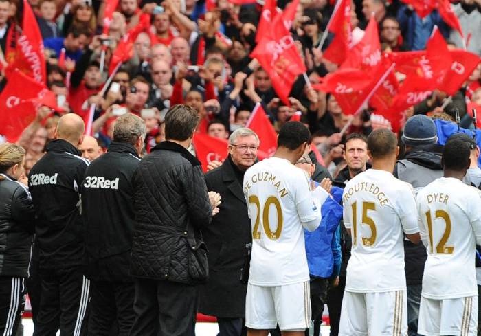 Sir Alex Ferguson (giữa) bước ra sân Old Trafford, Manchester, Anh trước trận Man Utd – Swansea City ngày 12/5/2013. Ảnh: AFP