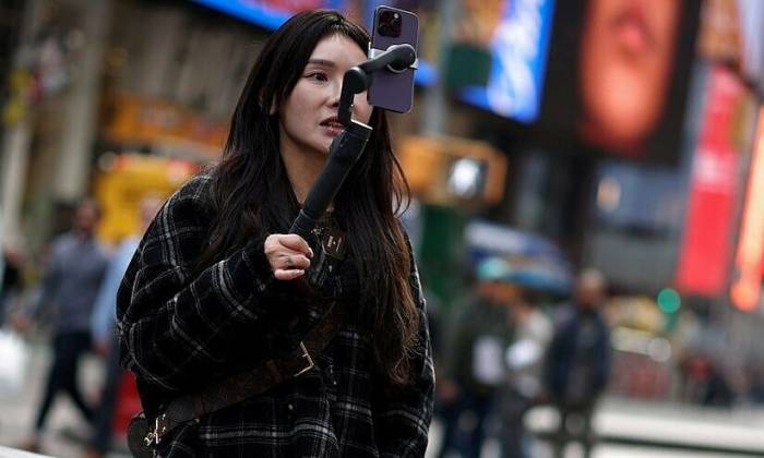 Một phụ nữ quay video để đăng lên TikTok tại Quảng trường Thời đại ở New York, Mỹ, ngày 13/3/2024. Ảnh: Reuters