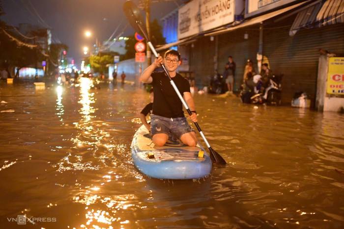 Nam thanh niên chèo thuyền kayak qua đoạn đường ngập sâu hơn một mét trên đường Phan Huy Ích, tối 30/9. Ảnh: Thanh Tùng
