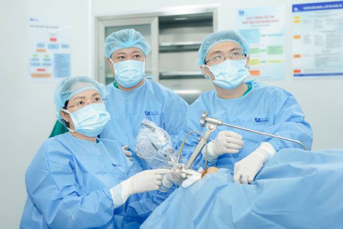 Bác sĩ Hằng (ngồi) đang phẫu thuật nội soi vi phẫu thanh quản cắt u cho chị Trà. Ảnh: Bệnh viện Đa khoa Tâm Anh