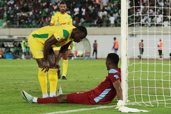 Thủ thành Marcel Dandjinou (ngồi trên sân) cùng trung vệ Mohamed Tijani (trái) trong trận Nigeria – Benin trên sân Godswill Akpabio, Akwa Ibom, Nigeria ngày 14/10/2025 thuộc vòng loại World Cup 2026 khu vực châu Phi. Ảnh: Reuters
