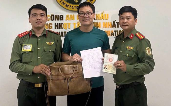 Anh Trần Văn Thạch nhận lại chiếc cặp chứa 50 triệu đồng, 3.000 USD và giấy tờ bỏ quên trong xe đẩy tại sân bay. Ảnh: Cục Quản lý xuất nhập cảnh
