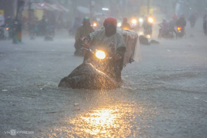 Nước chảy cuồn cuộn trên đường Tô Ngọc Vân trong trận mưa lớn chiều 30/9, khiến người dân chật vật đi lại. Ảnh: Quỳnh Trần