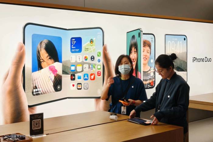 Hai nhân viên Apple Store Thượng Hải bên một bảng quảng cáo về mẫu điện thoại màn hình gập iPhone Duo. Ảnh: Trọng Đạt